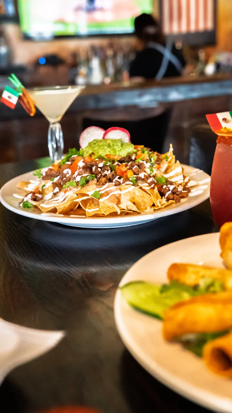Loaded nachos piled high, served with a cocktail at the bar