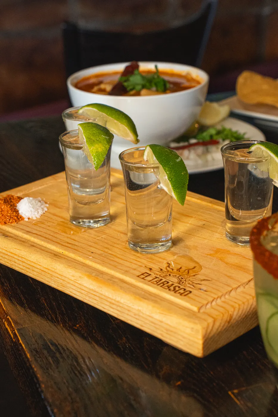 A tequila flight on a branded El Tarasco wood board with lime
